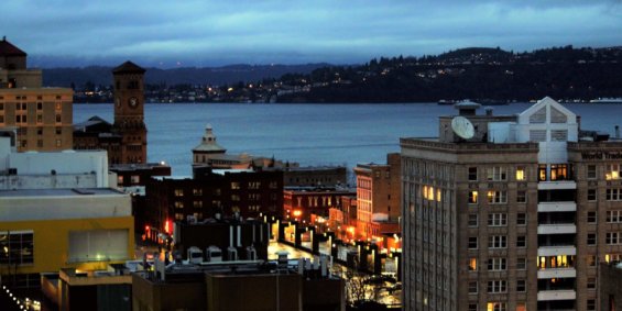 A downtown image of Tacoma at night with well lit buildings and a glistening body of water